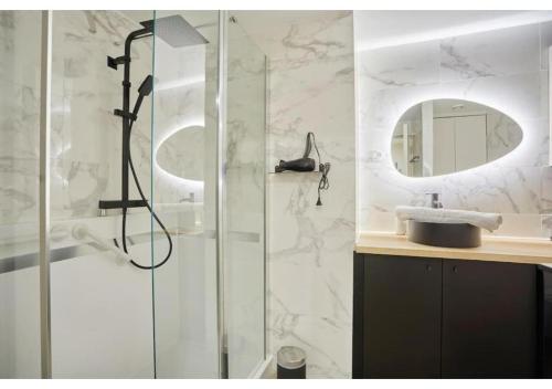 une salle de bain avec une douche avec un lavabo et un miroir dans l'établissement Apartment Le Marais Place des Vosges by Studio Prestige, à Paris