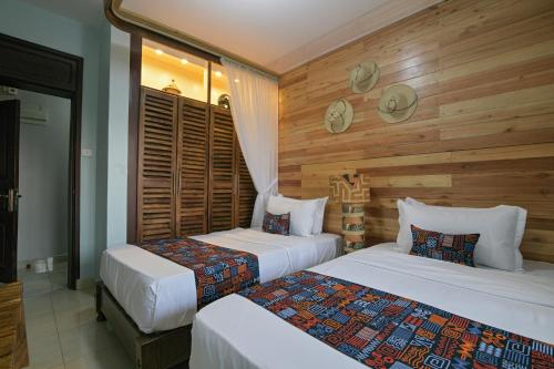 two beds in a room with wooden walls at Aqueduct 1359 Hotel Apartments in Kampala