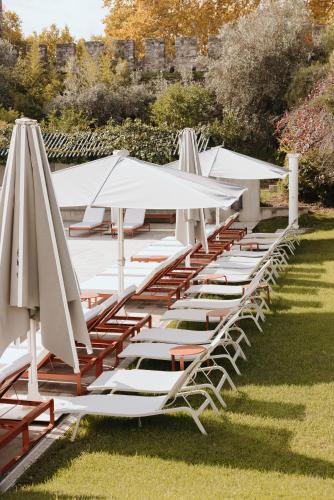 a row of lounge chairs and umbrellas on the grass at M'AR De AR Muralhas in Évora