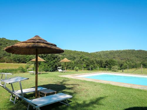 a pair of chairs and an umbrella next to a pool at Holiday Home Gaia by Interhome in Sticciano