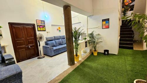 a living room with a blue couch and green carpet at Elephant House Boutique Stays- BHU- BLW in Varanasi