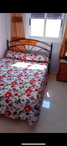 a bed with a floral comforter in a bedroom at Oued laou beach in Oued Laou
