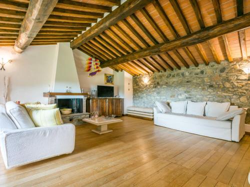 a living room with white couches and a stone wall at Holiday Home Bellavista - Villi by Interhome in Montieri