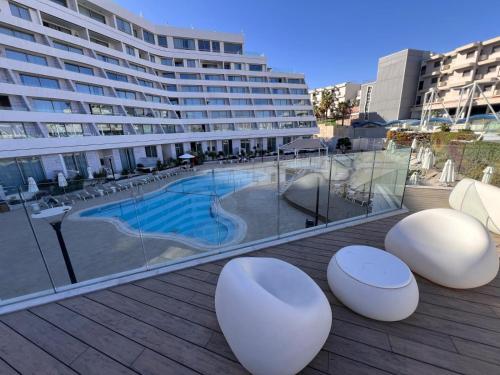a balcony with white chairs and a swimming pool at oR-Ya Suite in Eilat