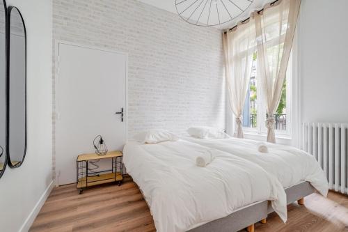 une chambre blanche avec un grand lit et une fenêtre dans l'établissement Appartement spacieux et lumineux en plein centre, à Saint-Étienne