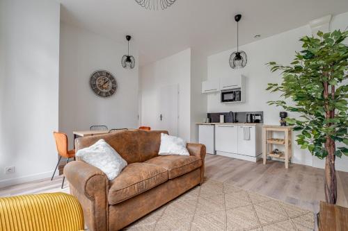 un salon avec un canapé marron et une cuisine dans l'établissement Appartement spacieux et lumineux en plein centre, à Saint-Étienne