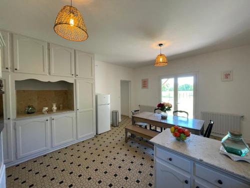 une cuisine avec des placards blancs, une table et un comptoir dans l'établissement Maison de caractère avec jardin, à Jarnac