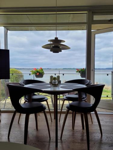 a dining room with a table and chairs and a large window at Hejlsminde ferie- og badeby in Hejls