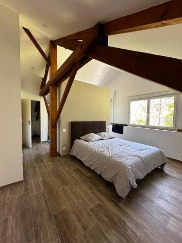- une chambre avec un grand lit et des poutres apparentes dans l'établissement Le Grand Tissac Maison dans le Quercy, à Cazes-Mondenard