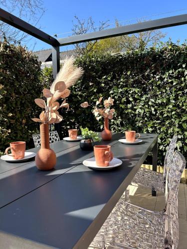 a black table with cups and flowers on it at Charlotte Lodge-House 4 pers-wifi-parking-Dinard in Dinard