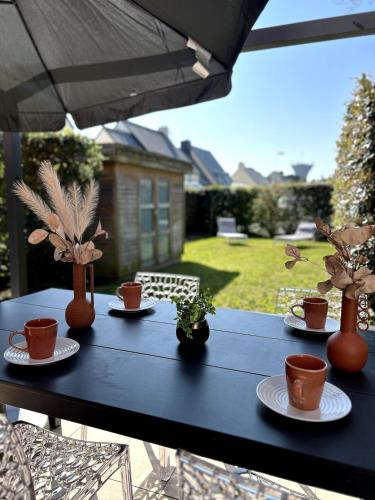 a table with cups and potted plants on it at Charlotte Lodge-House 4 pers-wifi-parking-Dinard in Dinard