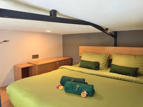 a bedroom with a large bed with green sheets at The Jungle Hostel Canggu in Canggu