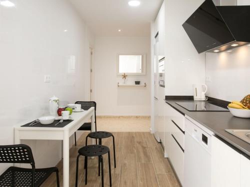 Una cocina blanca con una mesa pequeña y sillas. en Apartment Ercén by Interhome, en Rincón de la Victoria