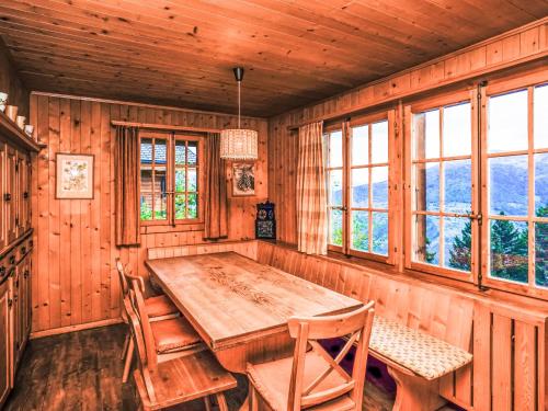 uma mesa de madeira e cadeiras num quarto com janelas em Chalet La Capsule by Interhome em Les Collons