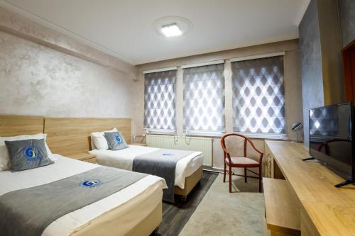 una camera d'albergo con due letti e una TV a schermo piatto di Ex G Hotel a Skopje