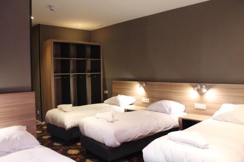 a hotel room with three beds with white sheets at Aston City Hotel in Amsterdam