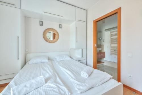 a white bedroom with a large bed and a mirror at Kamienica Sopocka by NorthSide Apartments in Sopot
