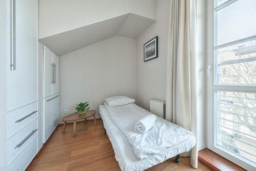 a small white room with a bed and a window at Kamienica Sopocka by NorthSide Apartments in Sopot