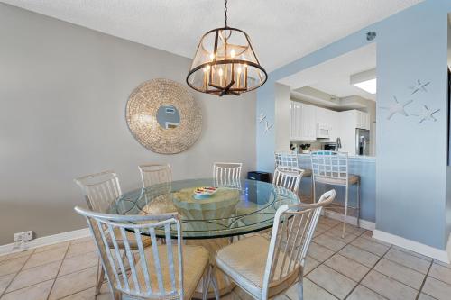a dining room with a glass table and chairs at Beach Colony W7C - Covered Parking Included in Pensacola