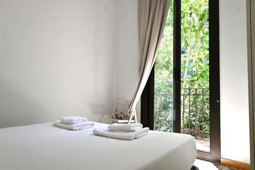 a white bed with three towels on top of it at Homenfun Barcelona Sants Estación in Barcelona