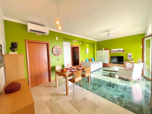 a living room with green walls and a table and chairs at D1MORA LagoBlu - private beach and lake view in Toscolano Maderno