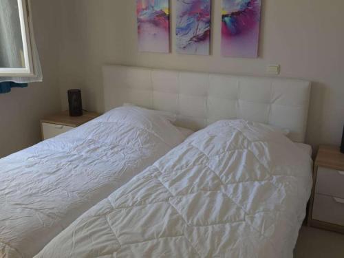 ein weißes Bett in einem Schlafzimmer mit Gemälden an der Wand in der Unterkunft T3 climatisé avec jardin à 200 m de la plage - FR-1-100-249 in Cavalaire-sur-Mer
