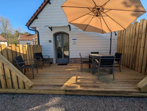 a wooden deck with a table and an umbrella at Gite Valloires piscine chauffée in Rue