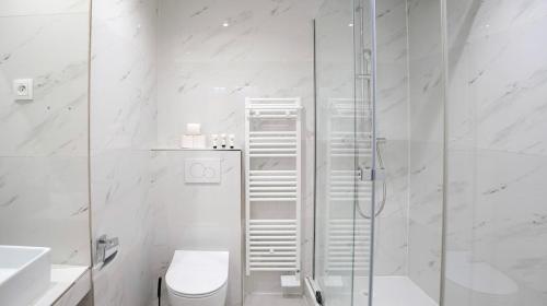une salle de bain blanche avec douche et toilettes dans l'établissement Modern Luxury Apartment Style & Serenity, à Paris