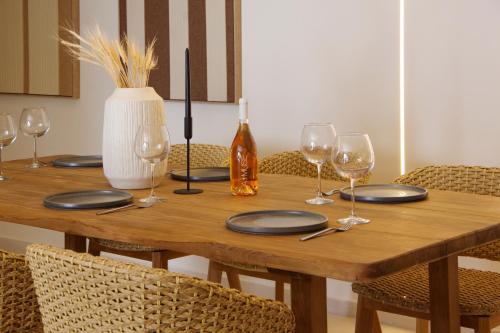 a wooden table with plates and wine glasses on it at Pnoe Villas Syros in Megas Yialos-Nites