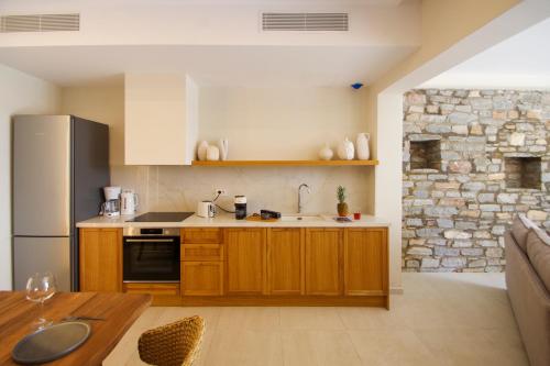 a kitchen with wooden cabinets and a stone wall at Pnoe Villas Syros in Megas Yialos-Nites