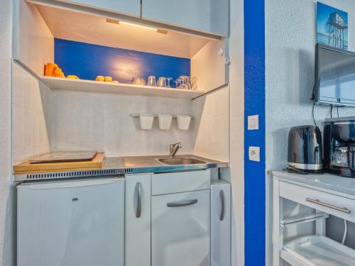 une petite cuisine avec des armoires blanches et un évier dans l'établissement Apartment Les Sables d'Argent-11 by Interhome, à Lacanau