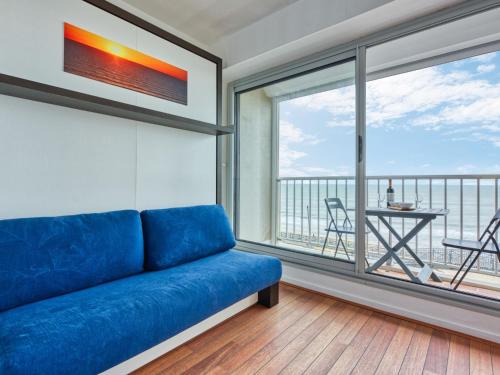 - un canapé bleu dans une chambre avec une grande fenêtre dans l'établissement Apartment Les Sables d'Argent-11 by Interhome, à Lacanau