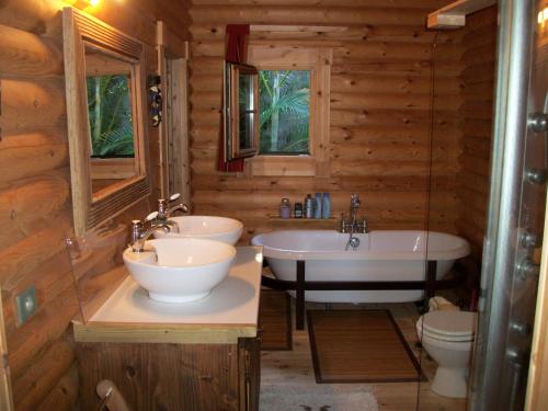 ein Badezimmer mit zwei Waschbecken, einer Badewanne und einem WC in der Unterkunft Le Chalet la Fontaine Saint Leu in Saint-Leu