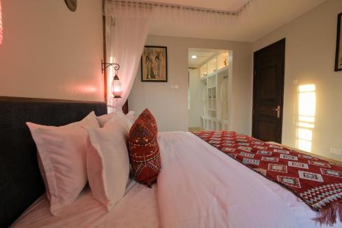 a bedroom with a bed with white pillows and a red blanket at Aqueduct 1359 Hotel Apartments in Kampala