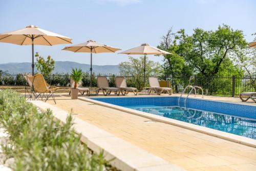 a swimming pool with chairs and umbrellas next to at Vila sa bazenom Vrnjačka Idila in Vrnjačka Banja