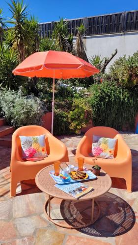 deux chaises oranges, une table et un parasol dans l'établissement Villa Palm' Issambres 6-7 personnes, clim, avec piscine, jardin et parking privés, à La Garonnette-Plage