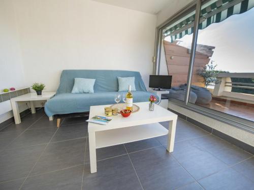 un salon avec un canapé bleu et une table dans l'établissement Studio Le Quai aux Fleurs-7 by Interhome, au Grau-du-Roi