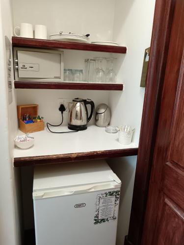 a kitchen with a tea kettle on a shelf above a refrigerator at Berg en Zee Guesthouse in Gordonʼs Bay