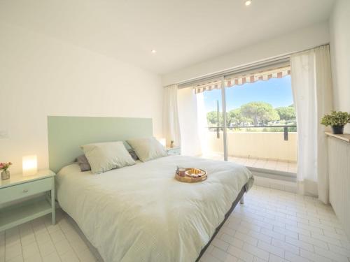 une chambre blanche avec un grand lit et une fenêtre dans l'établissement Apartment Le Serpent de Mer-8 by Interhome, au Grau-du-Roi