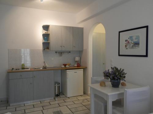 a kitchen with white cabinets and a table in it at Nissiotiko Studios & Apartments in Drios