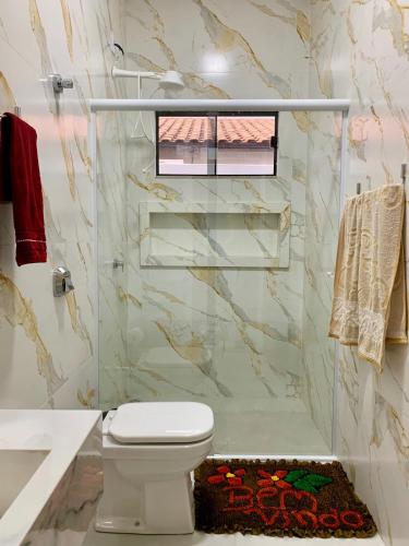 a bathroom with a toilet and a glass shower at casa grande e confortavel in Sinop