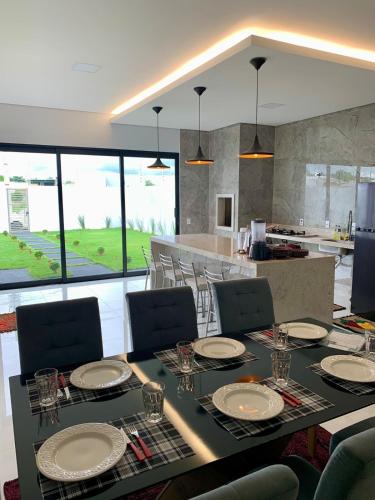 a dining room with a table and a kitchen at casa grande e confortavel in Sinop