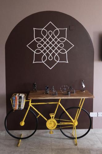 a table with a yellow bike in front of a wall at Aqueduct 1359 Hotel Apartments in Kampala