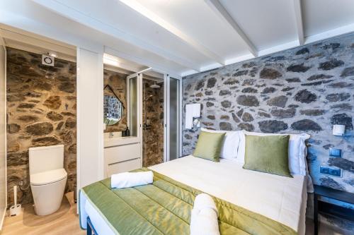 ein Schlafzimmer mit einem Bett und einer Steinwand in der Unterkunft Social Lodge Galinho House in Estreito da Calheta