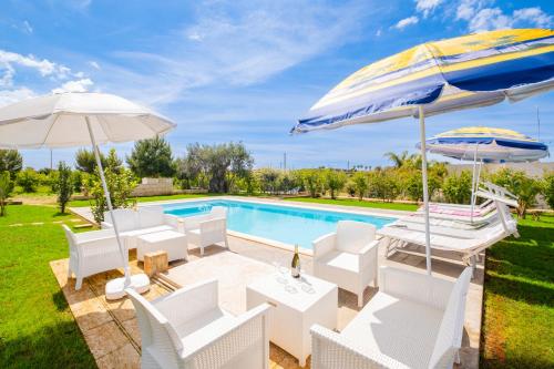 a villa with a swimming pool with white chairs and umbrellas at Villa Ciullo con Piscina Privata a Pescoluse by HDSalento in Marina di Pescoluse