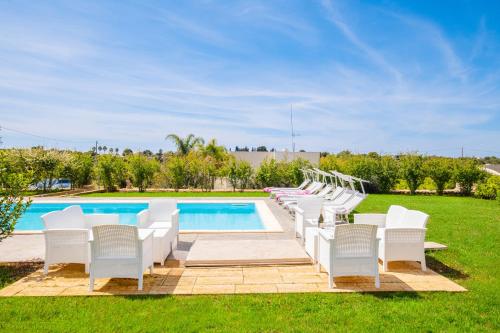 a group of white chairs next to a swimming pool at Villa Ciullo con Piscina Privata a Pescoluse by HDSalento in Marina di Pescoluse