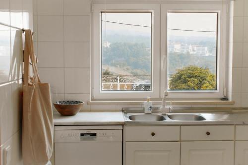 a kitchen with a sink and two windows at Casa Isa Bela in Buarcos
