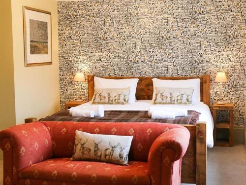 a bedroom with a bed and a red couch at The Quay Rooms in Wells next the Sea
