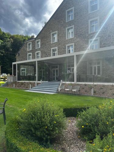 a large brick building with benches in front of it at Moulin de Daverdisse in Daverdisse