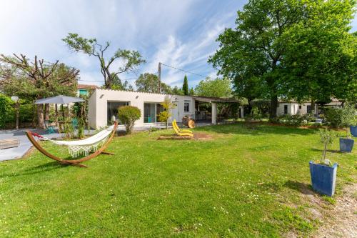 a yard with a hammock and a house at Vacances révées au Pin Parasol in Le Thor